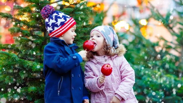 Two little kids eating crystalized apple on Christmas market