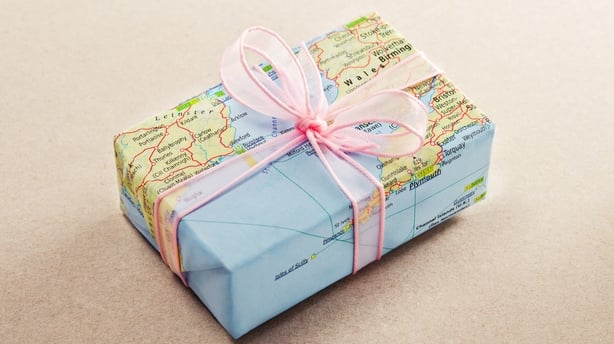 A bon voyage gift wrapped with map paper and pink bow