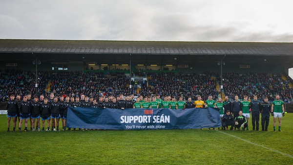 The two teams display a banner in support of Sean Cox before the game