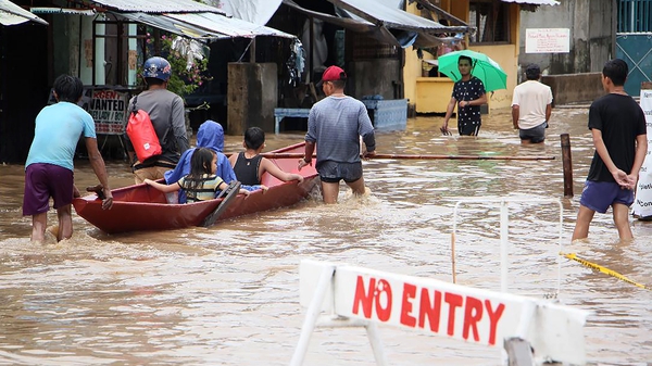 People wade through a flooded street in the town of Baao in Camarines Sur province