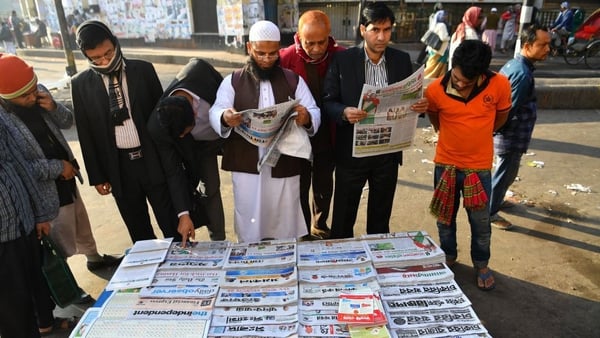 Bangladeshi people read newspapers carrying headlines on the general election results