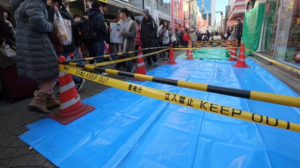 Pedestrians walk past the roped-off crime scene in Tokyo this morning