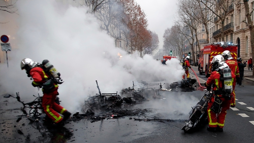 Firefighters extinguish vehicles on fire near the Seine river as clashes erupt in Paris