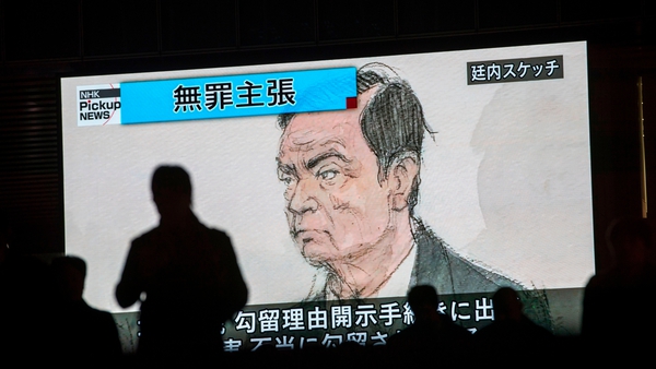Japanese pedestrians pass by a TV screen displaying a sketch of former Nissan chairman Carlos Ghosn in court earlier this week