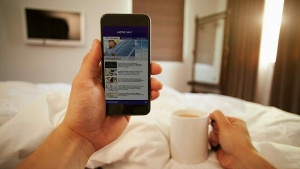 Man In Bed Looking At News Website On Mobile Phone