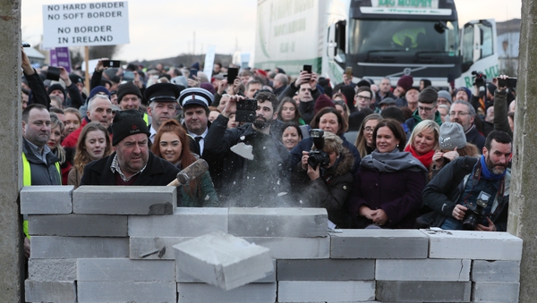 Sinn Fein leader Mary Lou McDonald and deputy leader Michelle O'Neill (both at right) watch as a man knocks down a mock border wall in Carrickcarnan, Co Louth