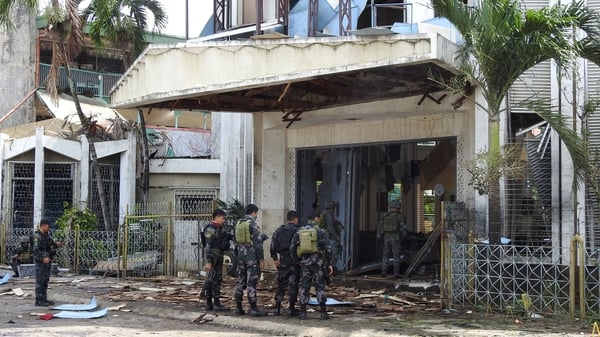 Police officers and soldiers stand outside the bomb-hit church in Jolo, Sulu province