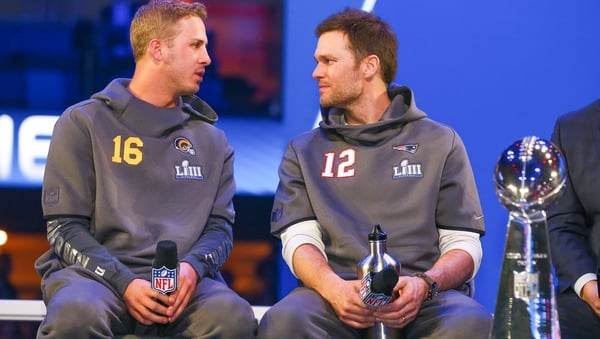 New England Patriots quarterback Tom Brady (12) and Los Angeles Rams quarterback Jared Goff (16) sit beside the Vince Lombardi Trophy