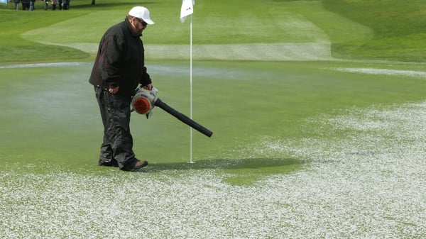 A member of the ground staff clears hail form the first green
