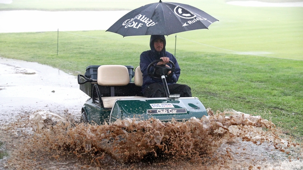 A staff member drives along the rain-sodden course