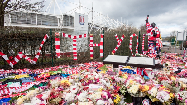 Tributes of flowers, scarves and shirts adorn a statue of Gordon Banks