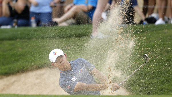 The leader hits out of the sand on his final hole on Saturday