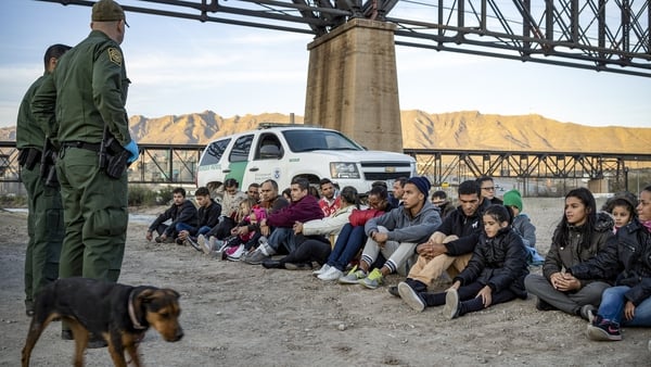A group of about 30 migrants, who had just crossed the border, sit on the ground near US Border Patrol agents in 2019 (File pic