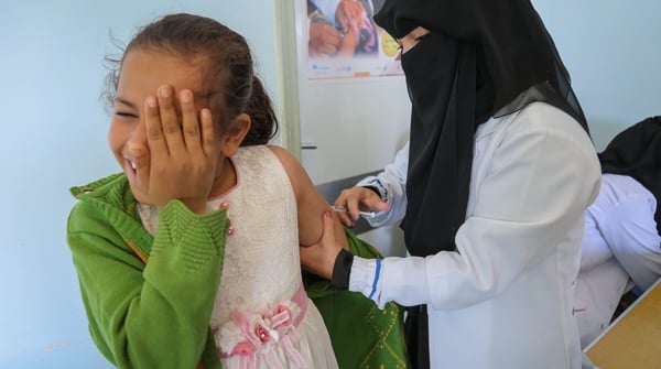 A young girl looks away as she gets the measles vaccine in Yemen