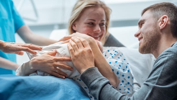 In the Hospital Midwife Gives Newborn Baby to a Mother to Hold, Supportive Father Lovingly Hugging Baby (iStock/PA)