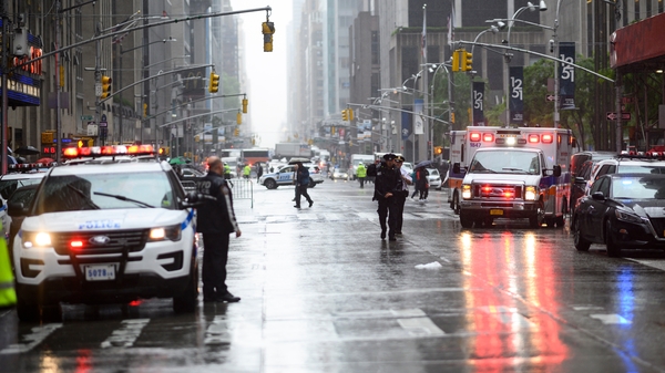Police officers stand near emergency services vehicles after a helicopter crash-landed on top of a building in Manhattan