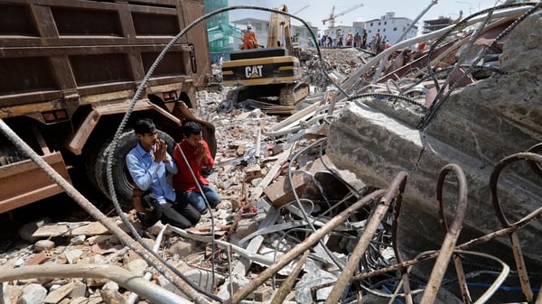 Men pray for their missing relatives at the site of a collapsed building in Preah Sihanouk province