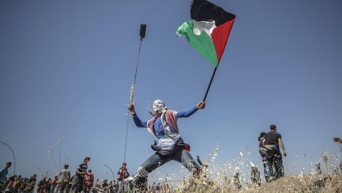 A Palestinian protester throws stones by his slingshot during the clashes near the border between Israel and Gaza in May