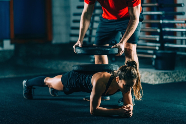 Cross training. Female athlete resisting weight of heavy barbells