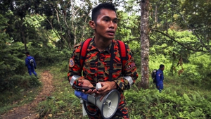 A Malaysian Fire and Rescue Department officer uses a loud speaker to play the voice of Nóra's mother during the search operation