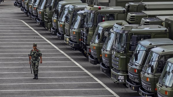 A member of China's People's Armed Police Force walks by vehicles gathered on the Shenzhen Bay Sports Centre