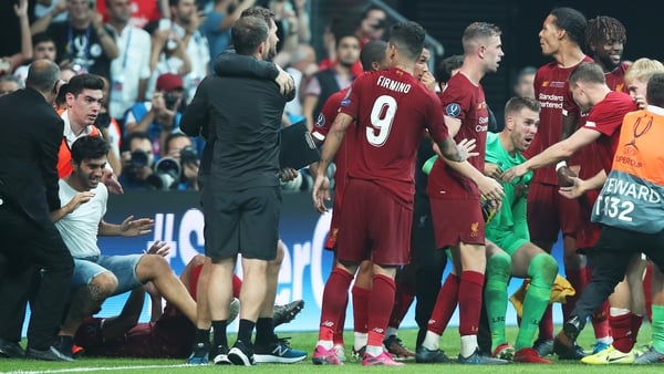 Adrian (green shirt) being helped by teammates after a pitch invader (L jeans shorts) rushed into him at the end of the penalty shootout