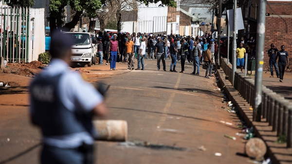 A group of men gather in front of a police station in Johannesburg's CBD as the unrest continues