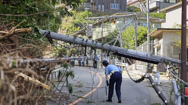A police officer ispects a fallen utility pole downed by winds caused by Typhoon Faxai in Kamakura