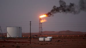 A gas flame behind pipelines in the desert at Khurais oil field