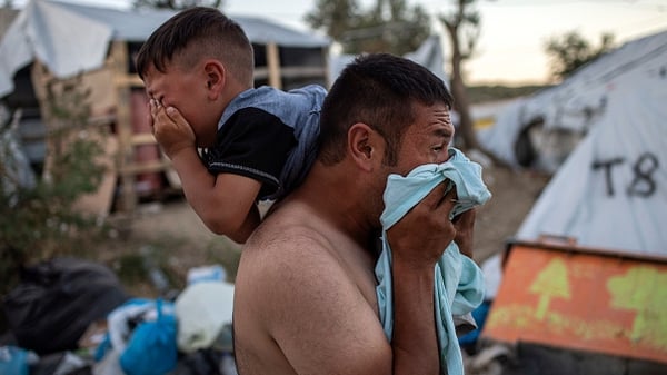 A man and a boy react after police fired tear gas during clashes outside the refugee camp of Moria