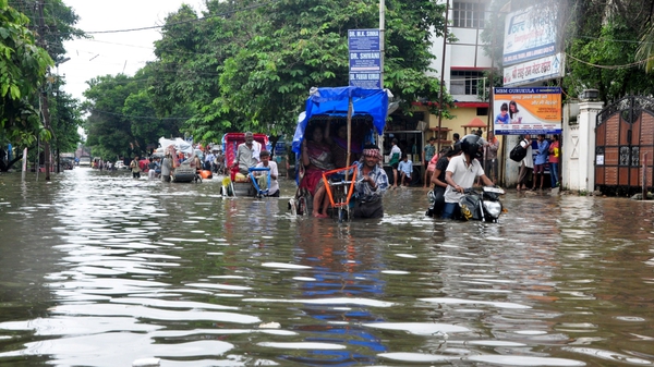 People use rickshaws to cross a flooded street in Patna, Bihar, India