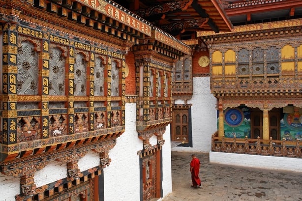 A monk walks among ornate carvings in a Punakha Temple
