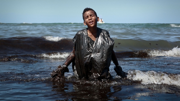 Photographer Leo Malafaia captured the boy emerging from the sea covered in oil (Photo by Leo Malafaia/AFP via Getty Images)