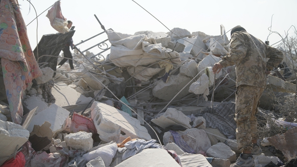 People walk among the rubble on the compound where Abu Bakr al-Baghdadi is believed to have died