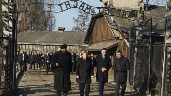 Angela Merkel began the visit by walking through a gate bearing the chilling Nazi message 'Arbeit macht frei'