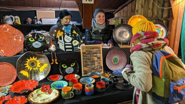 Agnes (left) and Anna (middle) serve a customer from their stall, Candeluna, at the Krakow Christmas Market (Jonjo Maudsley/PA)