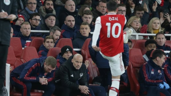 Per Mertesacker and Freddie Ljungberg look on as Mesut Ozil kicks his gloves in the air after he is subbed