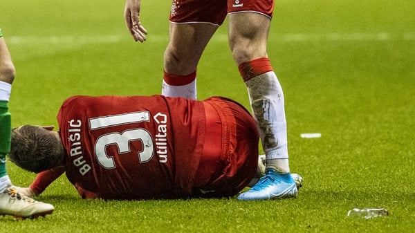 Barisic lies beside a glass bottle on the Easter Road pitch