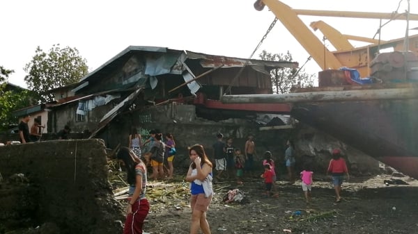 Villagers walk around a cargo ship washed ashore on Christmas Day in the typhoon-hit city of Ormoc