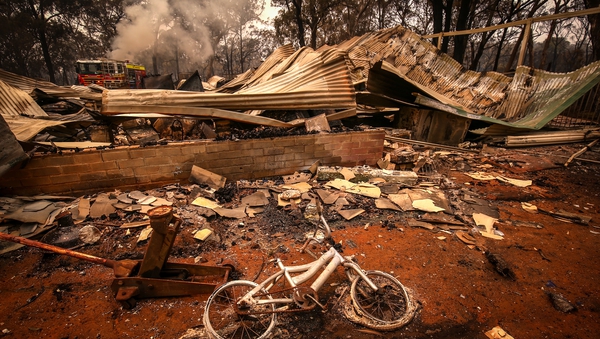 A burnt bicycle lies on the ground in front of a house destroyed by bushfires on the outskirts of Bargo near Sydney