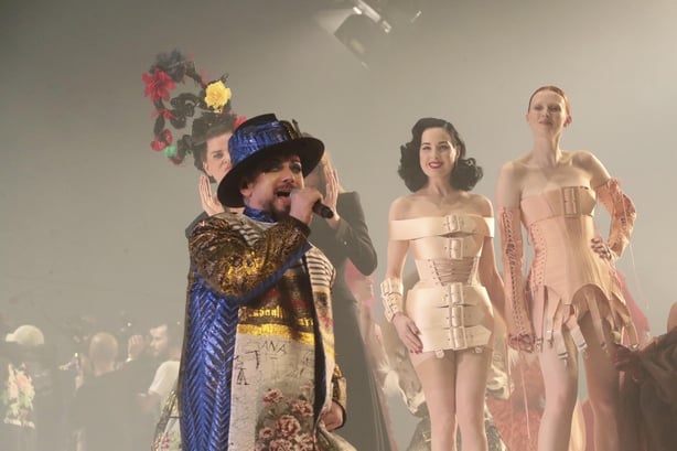 Boy George performs while Dita Von Teese and Karen Elson watch on