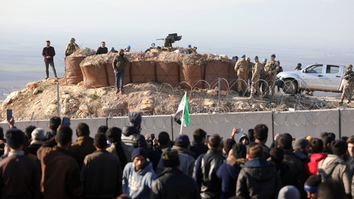 Syrian people gather near the Syrian-Turkish border