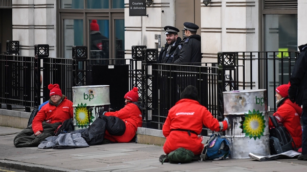 Greenpeace activists sit chained into oil barrels as they protest outside the headquarters of oil giant BP in London