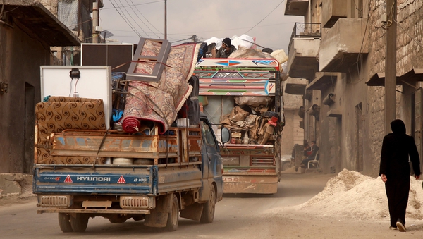 Vehicles carrying displaced people and their belongings drive through the town of Darret Ezza, northwest of Aleppo