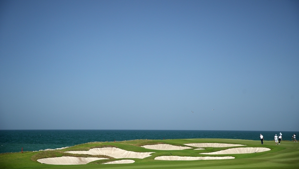 Competitors putt on the ninth green during the third round of the Oman Open at Al Mouj Golf