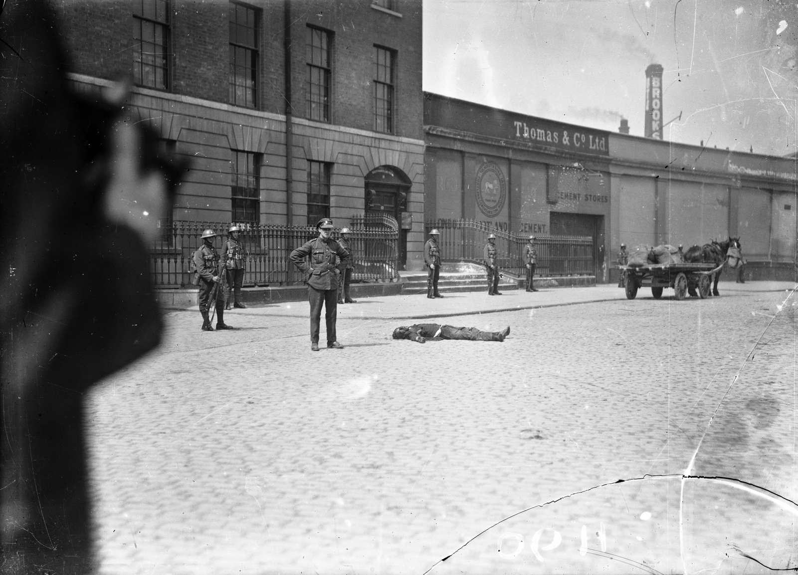 Image - A man lies dead on Beresford Place after the IRA attack on the Custom House. Image courtesy of the National Library of Ireland. NLI INDH 90