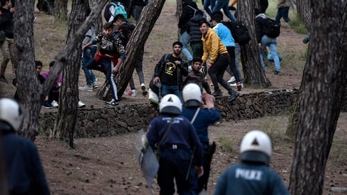 Migrants run from riot police after being pushed to go back to Moria camp from the port of Mytilene