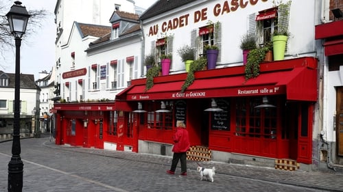 A woman walks her dog on a deserted street in Montmartre in Paris