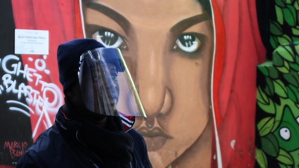 A man with a protective visor walks near Martim Moniz district, in Lisbon, Portugal