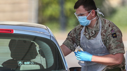 A member of the military takes a swab from a person at a drive-in Covid-19 testing centre at Chessington World of Adventures Resort in England